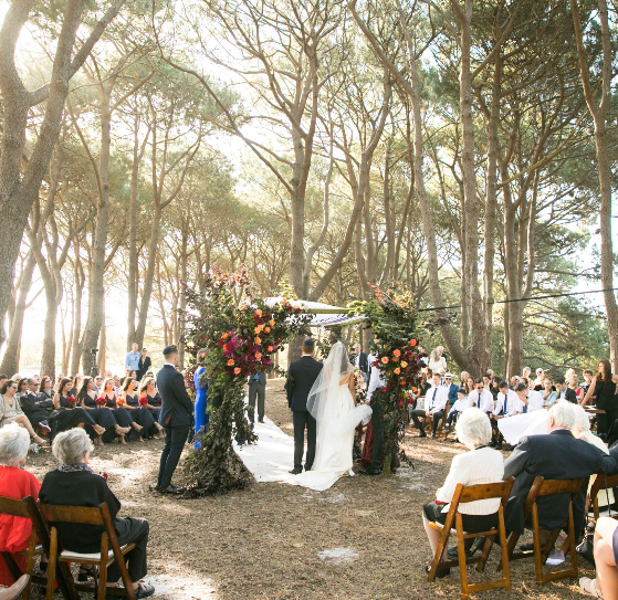 A couple standing under a chuppah at golden hour