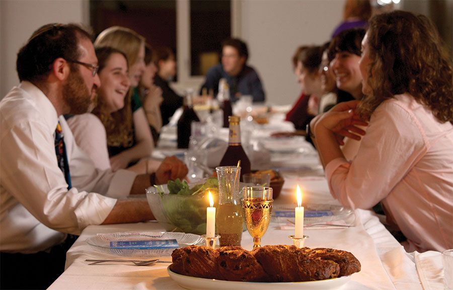 A Shabbat table with lit candles and challah