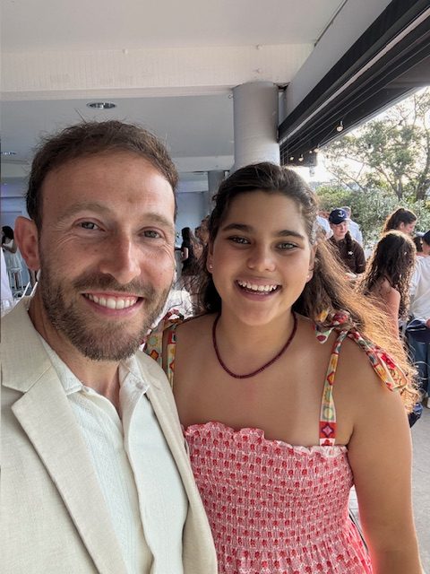 A smiling man and young girl posing together at a celebration