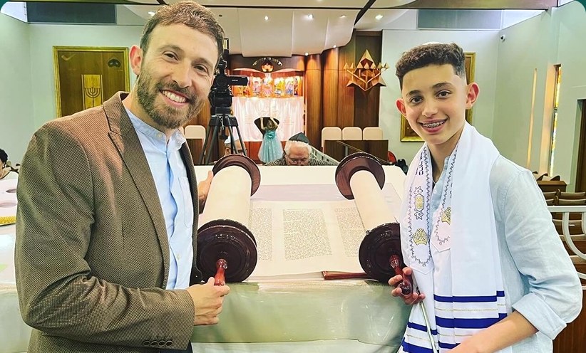 A child holding an open Torah scroll during a ceremony