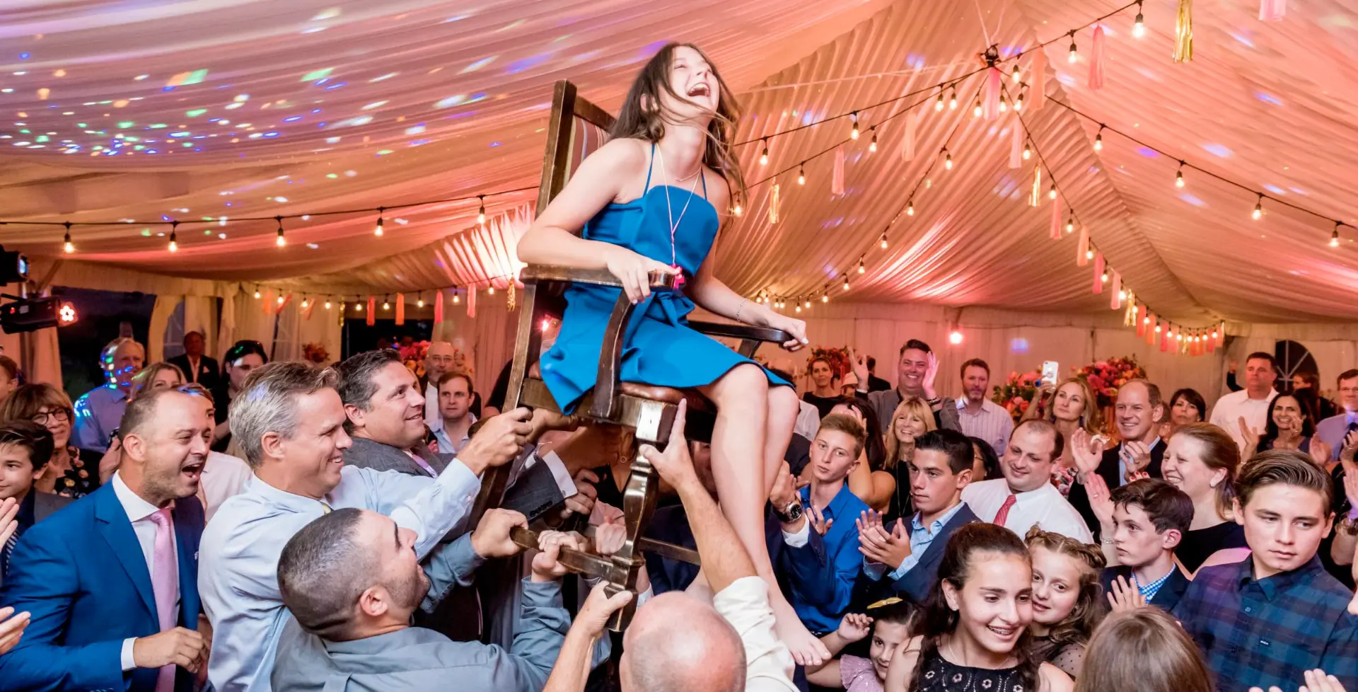 A young woman reading Torah at her Bat Mitzvah with family nearby
